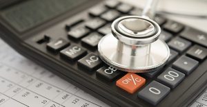 health care costs, stethoscope and calculator on bills for finance plan or health insurance.