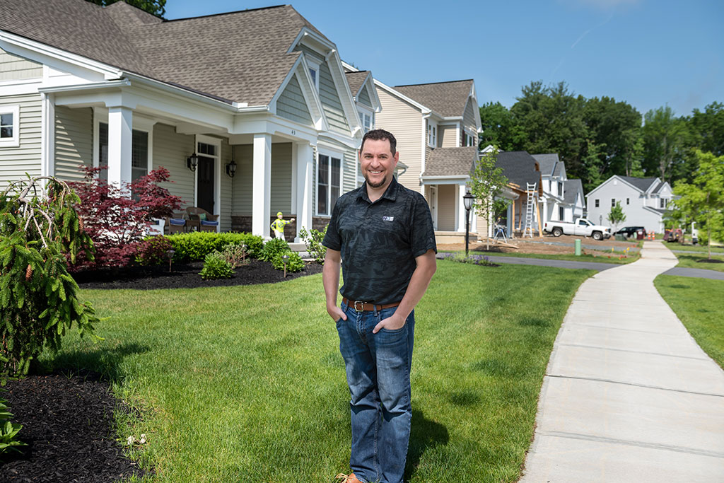 Man standing in front of homes in various states of construction